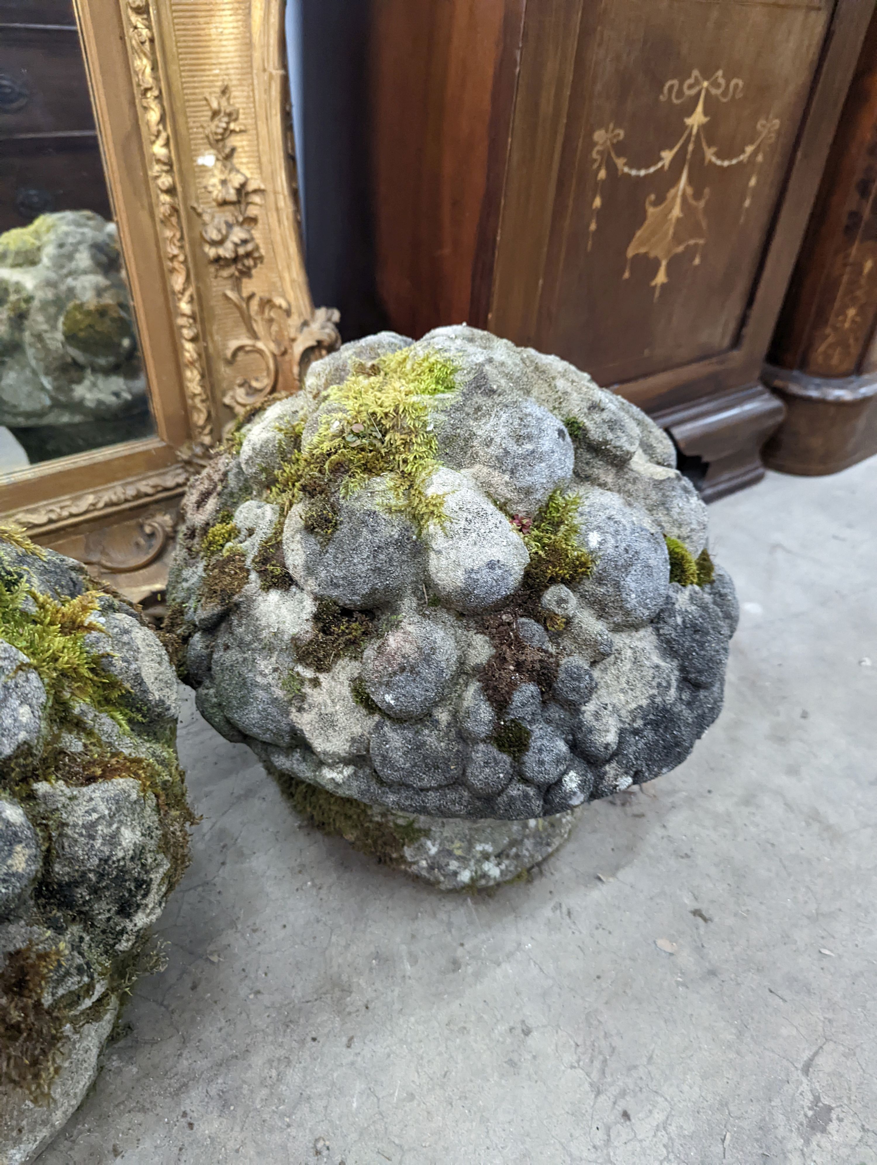 A set of three weathered reconstituted stone garden ornaments modelled as floral bunches, diameter 32cm, height 30cm